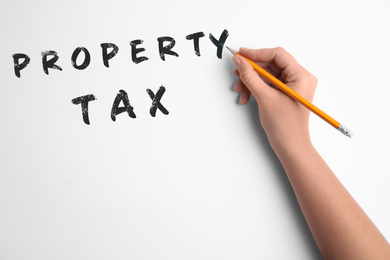 Image of Woman writing phrase Property Tax on white background, closeup