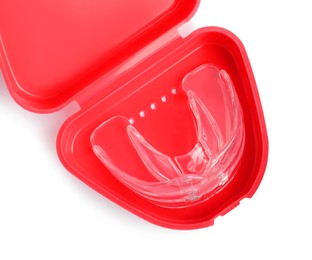 Photo of Transparent dental mouth guard in container isolated on white, top view. Bite correction