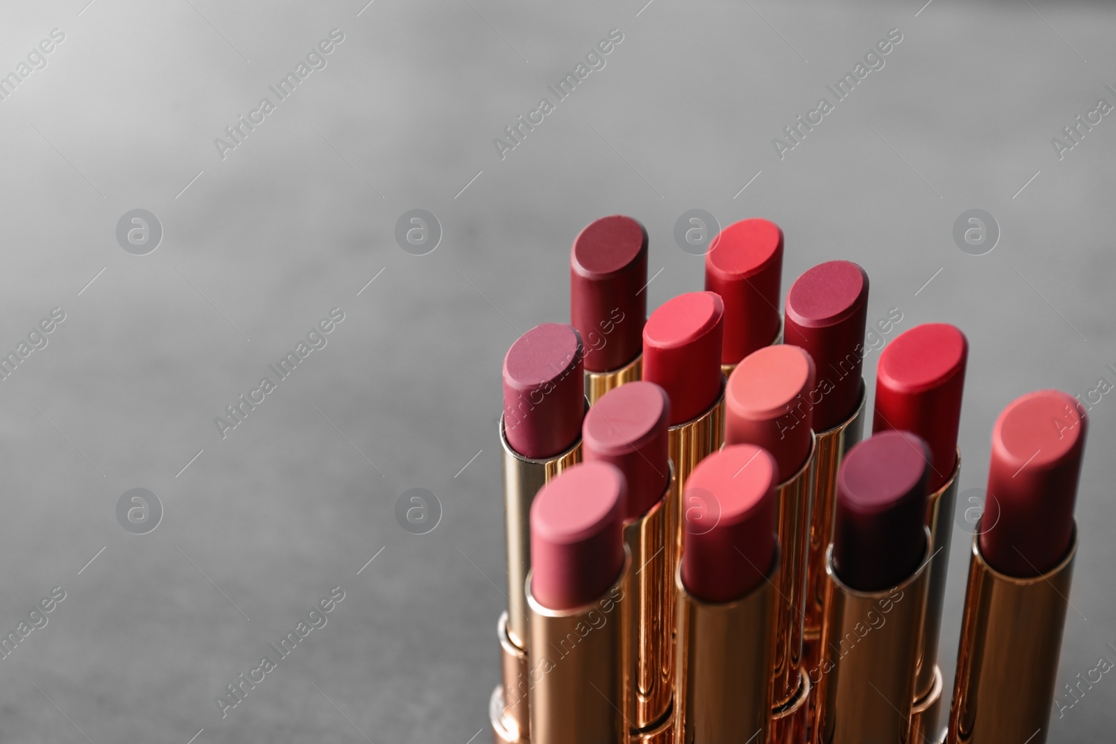 Photo of Set of bright lipsticks on grey background. Space for text