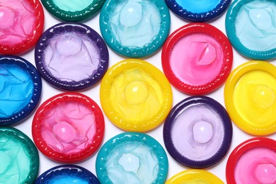 Colorful condoms on white background, flat lay. Safe sex