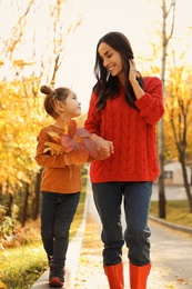 Happy woman with daughter walking in sunny autumn park