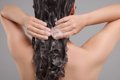 Photo of Woman washing hair on grey background, closeup