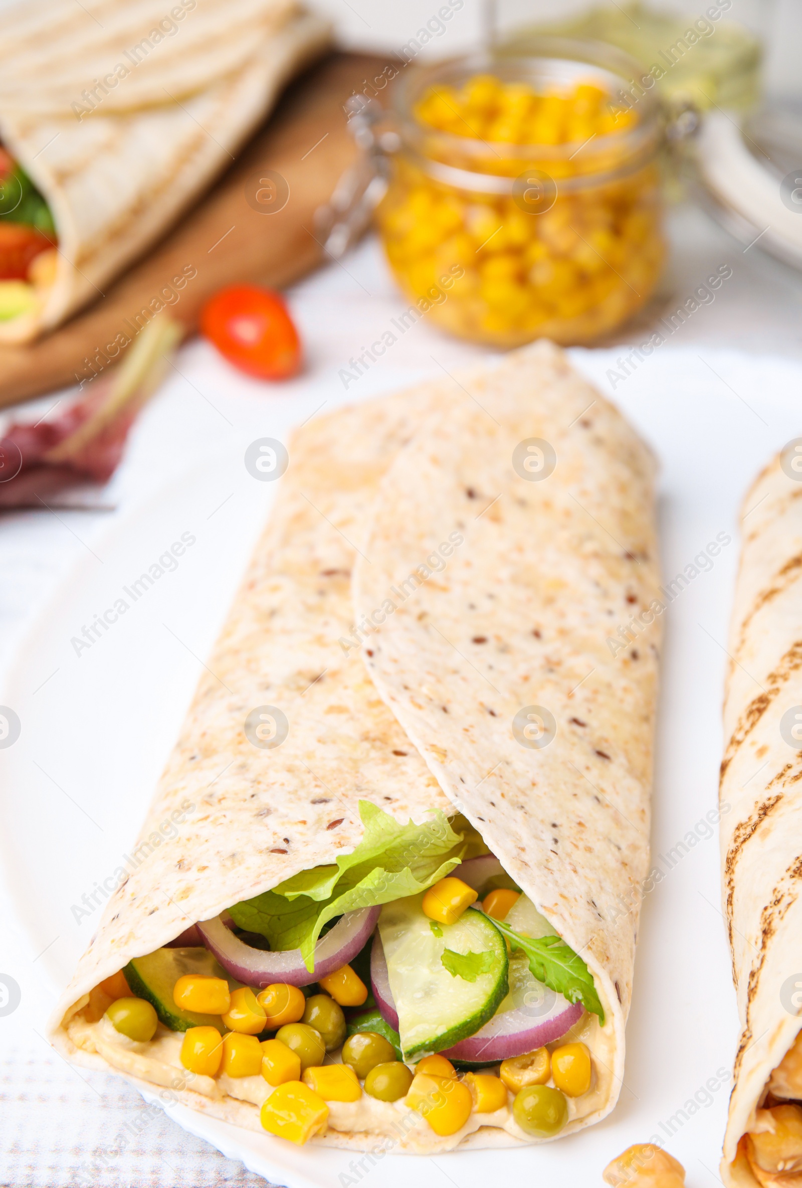 Photo of Delicious hummus wrap with vegetables on table