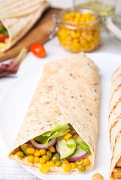 Photo of Delicious hummus wrap with vegetables on table