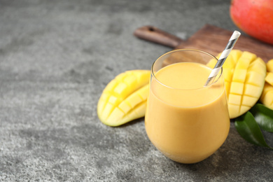 Photo of Fresh delicious mango drink on grey table. Space for text