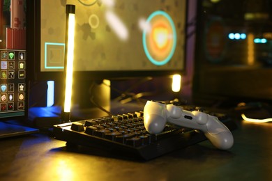 Playing video games. Computer monitor, keyboard and wireless controller on table indoors