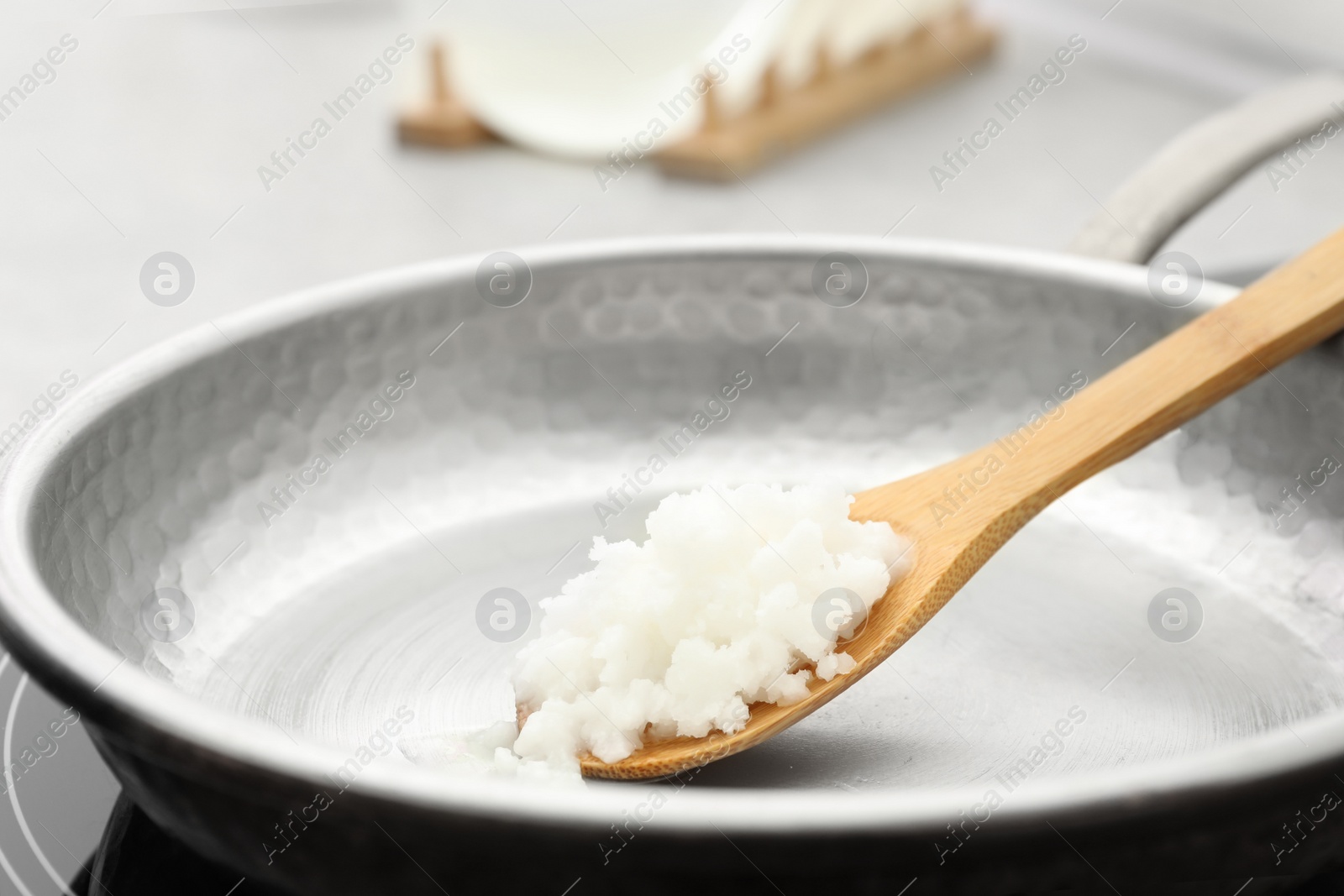 Photo of Frying pan with coconut oil on induction stove, closeup. Healthy cooking