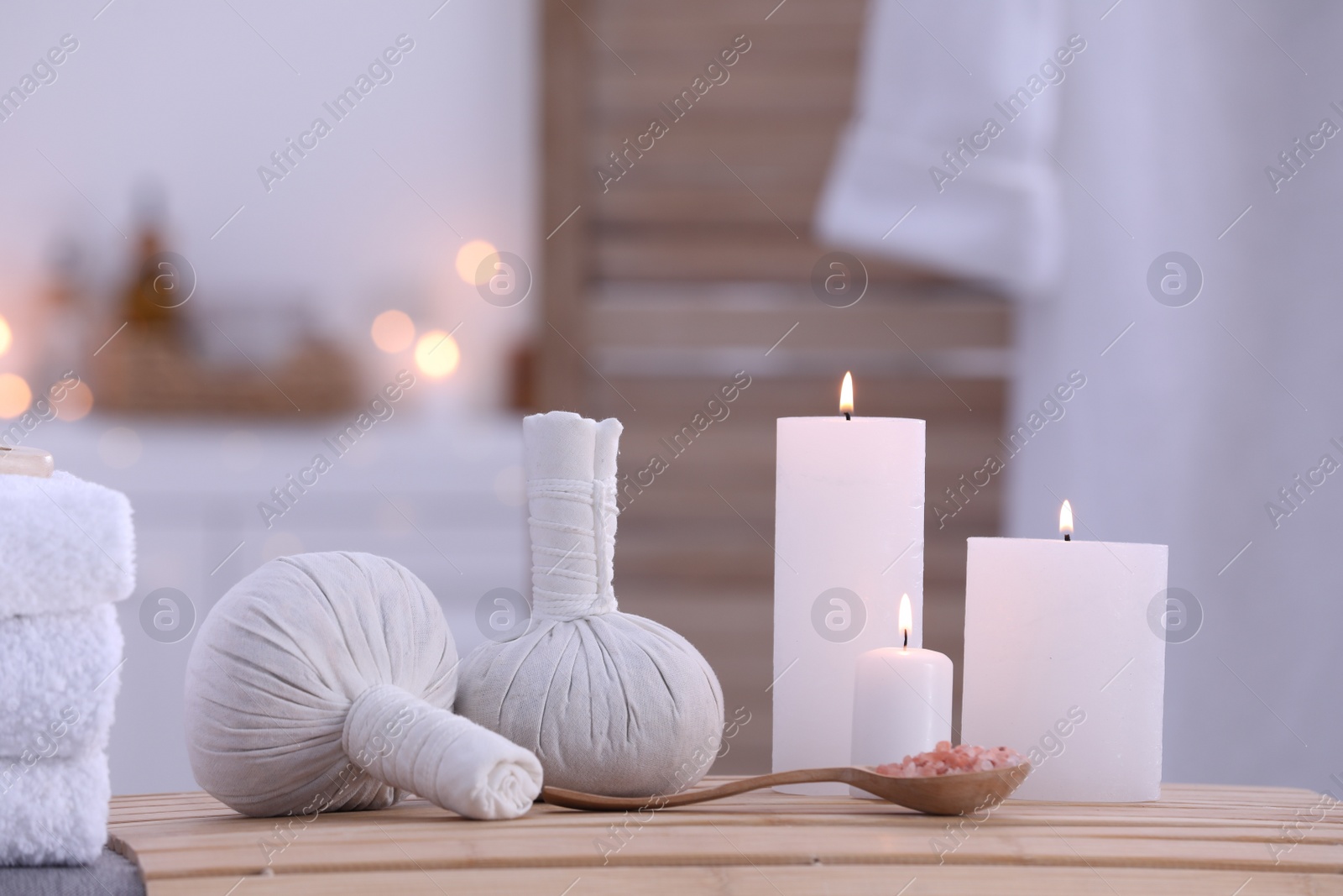 Photo of Spa composition with burning candles and herbal bags on massage table in wellness center