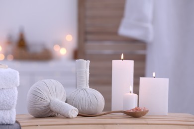 Spa composition with burning candles and herbal bags on massage table in wellness center