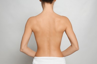 Photo of Back view of woman with perfect smooth skin on light grey background, closeup. Beauty and body care
