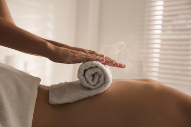 Image of Young woman receiving hot towel massage in spa salon, closeup
