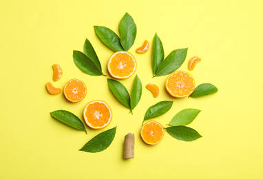 Photo of Flat lay composition with fresh green citrus leaves and tangerine slices on yellow background