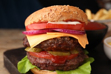 Photo of Tasty cheeseburger with patties and tomato on table, closeup
