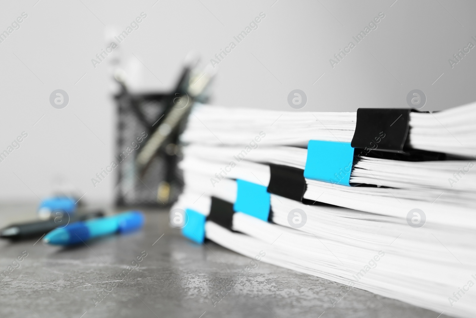 Photo of Stack of documents with binder clips on grey stone table, closeup view. Space for text