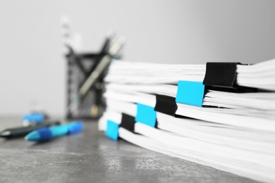 Stack of documents with binder clips on grey stone table, closeup view. Space for text