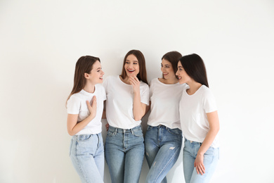 Photo of Beautiful young ladies in jeans and white t-shirts on light background. Woman's Day