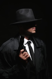 Photo of Old fashioned detective with gun on dark background