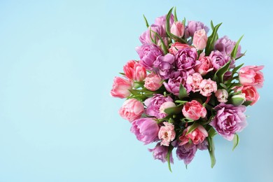Beautiful bouquet of colorful tulip flowers on light blue background, top view. Space for text