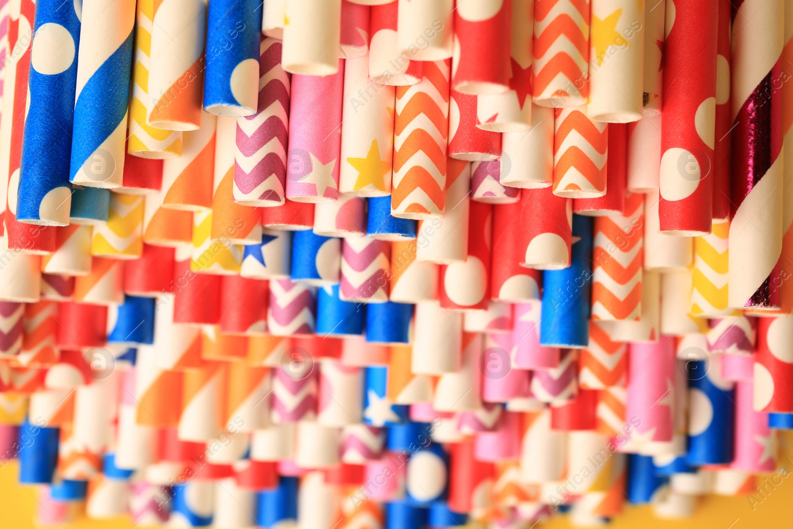 Photo of Many paper drinking straws on yellow background, closeup