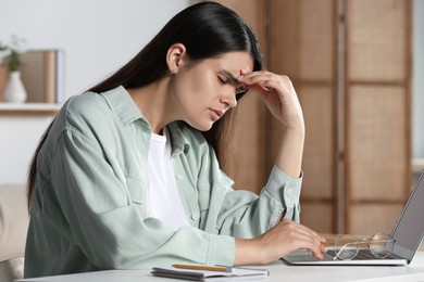 Young woman suffering from eyestrain at desk in office