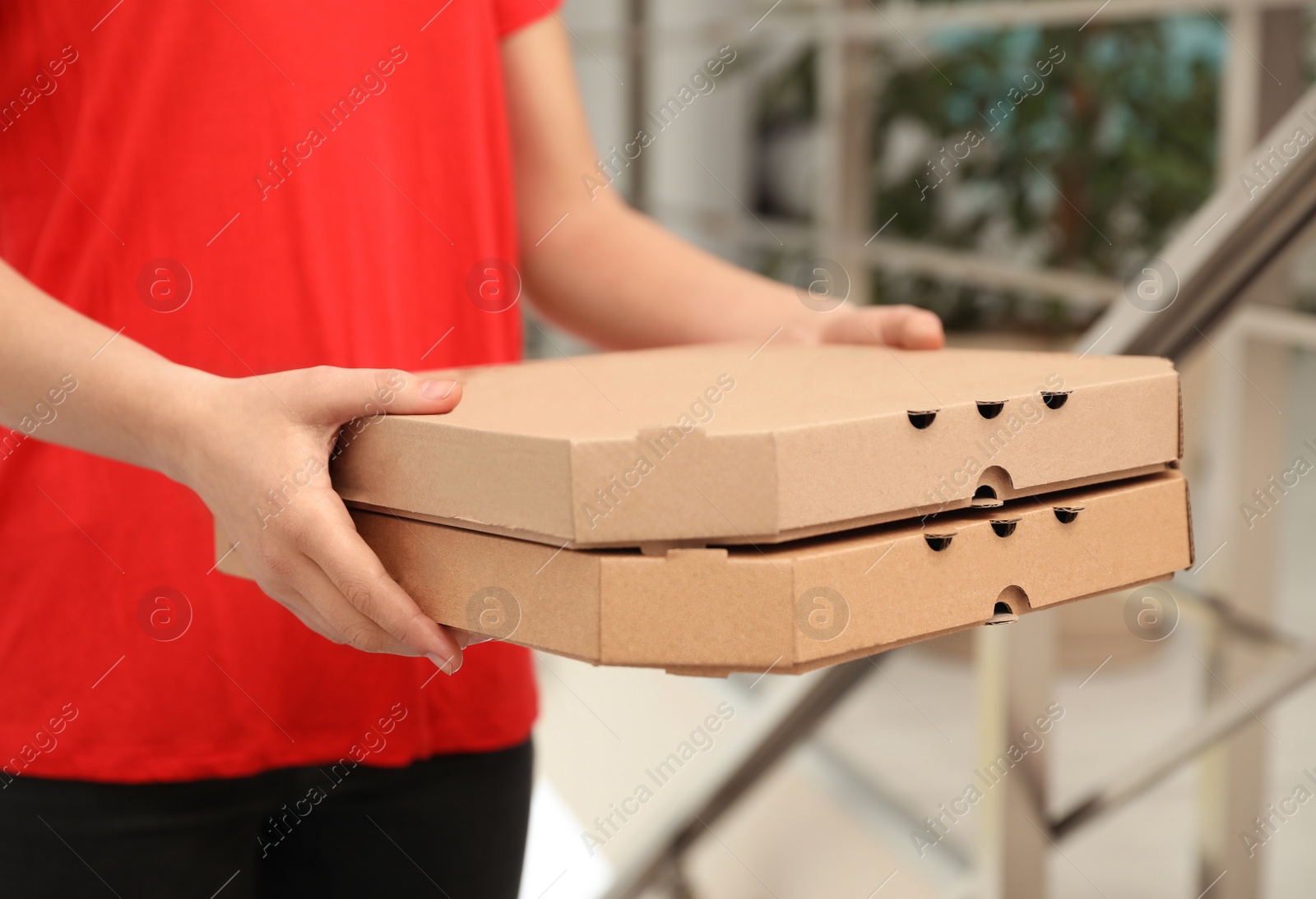 Photo of Female courier with pizza boxes indoors, closeup. Food delivery service