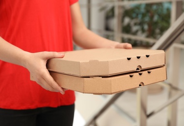 Female courier with pizza boxes indoors, closeup. Food delivery service