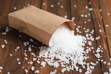 Overturned paper bag with natural sea salt on wooden table