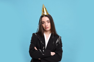 Sad woman in party hat on light blue background