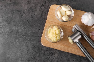 Garlic press, cloves and mince on wooden table, top view. Space for text