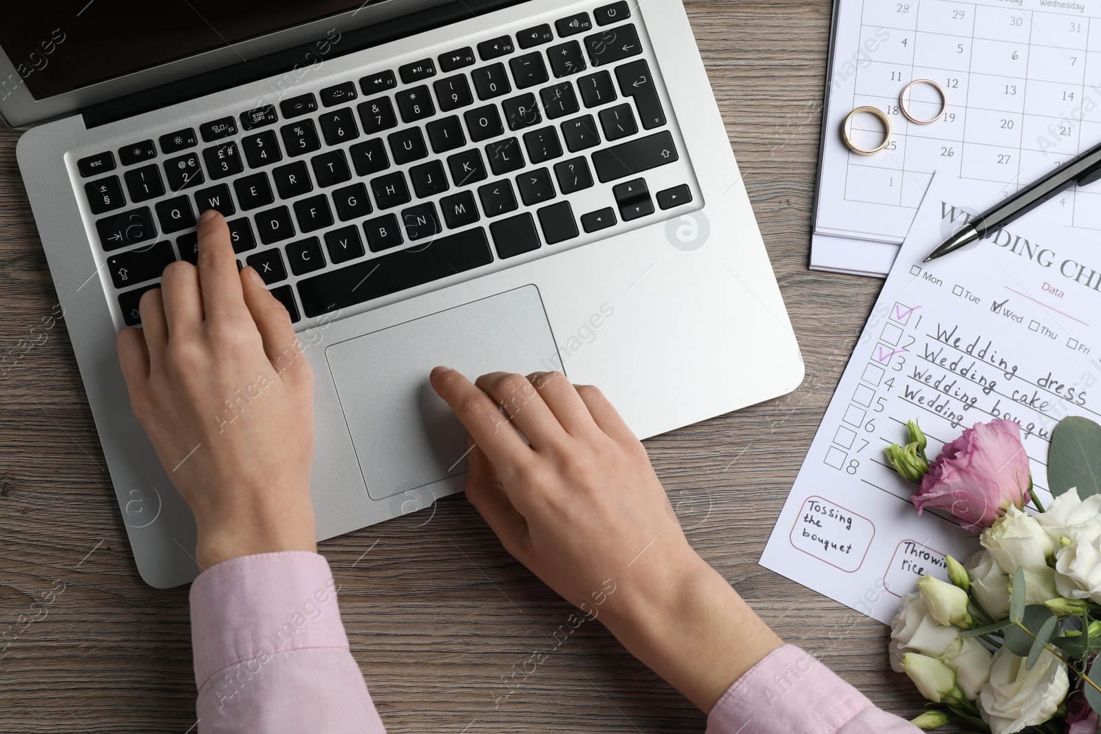 Photo of Woman with laptop and Wedding Checklist at wooden table, top view