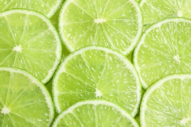 Photo of Fresh sliced ripe limes as background, top view