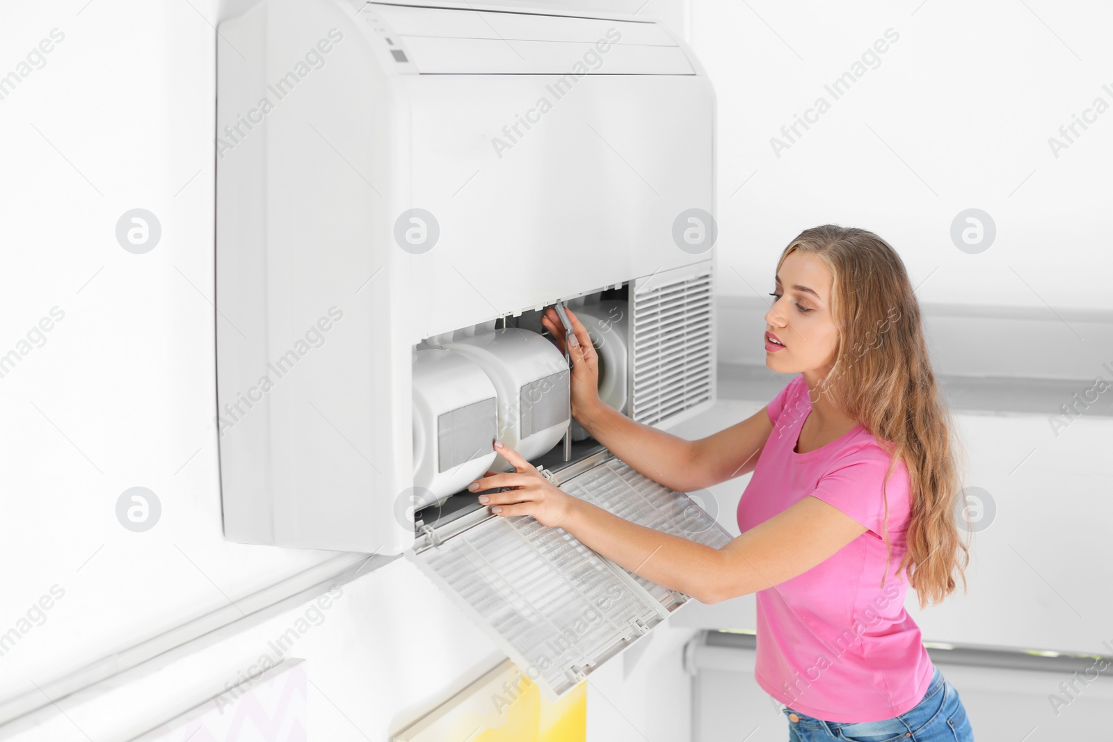 Photo of Young woman fixing air conditioner at home