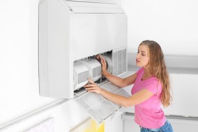 Photo of Young woman fixing air conditioner at home