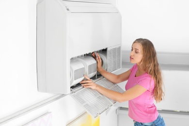 Young woman fixing air conditioner at home