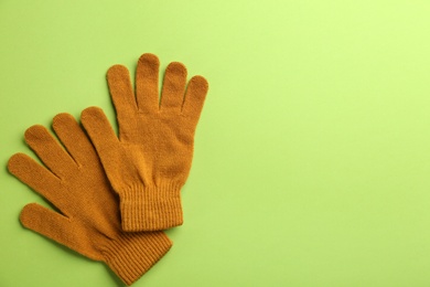 Pair of stylish woolen gloves on green background, flat lay. Space for text