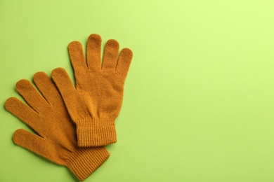 Photo of Pair of stylish woolen gloves on green background, flat lay. Space for text