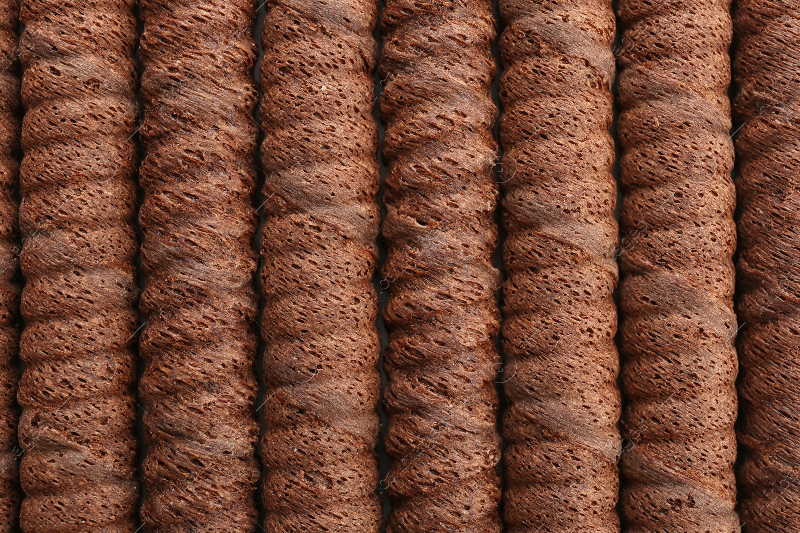 Photo of Delicious chocolate wafer rolls as background, top view. Sweet food