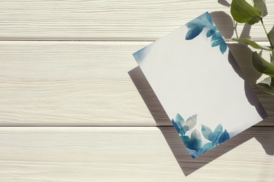 Beautiful card with word Invitation and green leaves on white wooden table, top view. Space for text