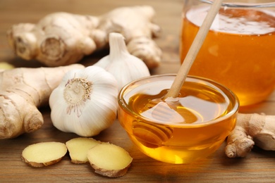 Photo of Ginger, garlic and honey on wooden table. Natural cold remedies