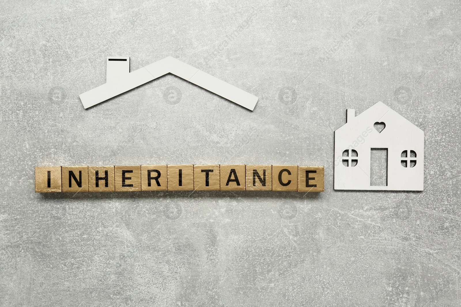 Photo of Word Inheritance made with wooden cubes and house model on grey background, flat lay