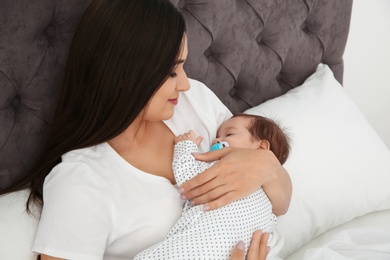Photo of Happy woman holding her sleeping baby on bed