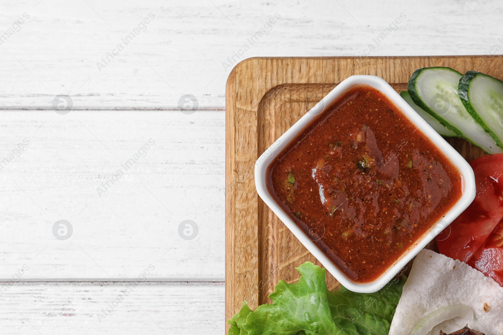 Photo of Wooden board with sauce on table, top view