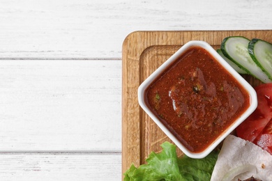 Wooden board with sauce on table, top view