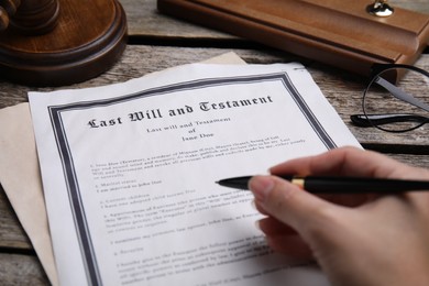 Photo of Woman signing last will and testament at table, closeup