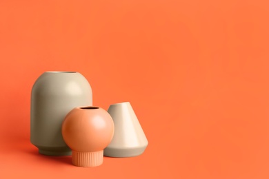 Photo of Stylish empty ceramic vases on orange background, space for text
