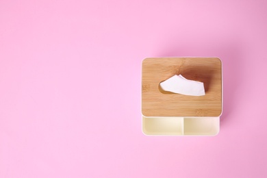 Photo of Holder with paper tissues on pink background, top view. Space for text