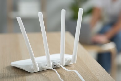 Photo of New modern Wi-Fi router on wooden table indoors