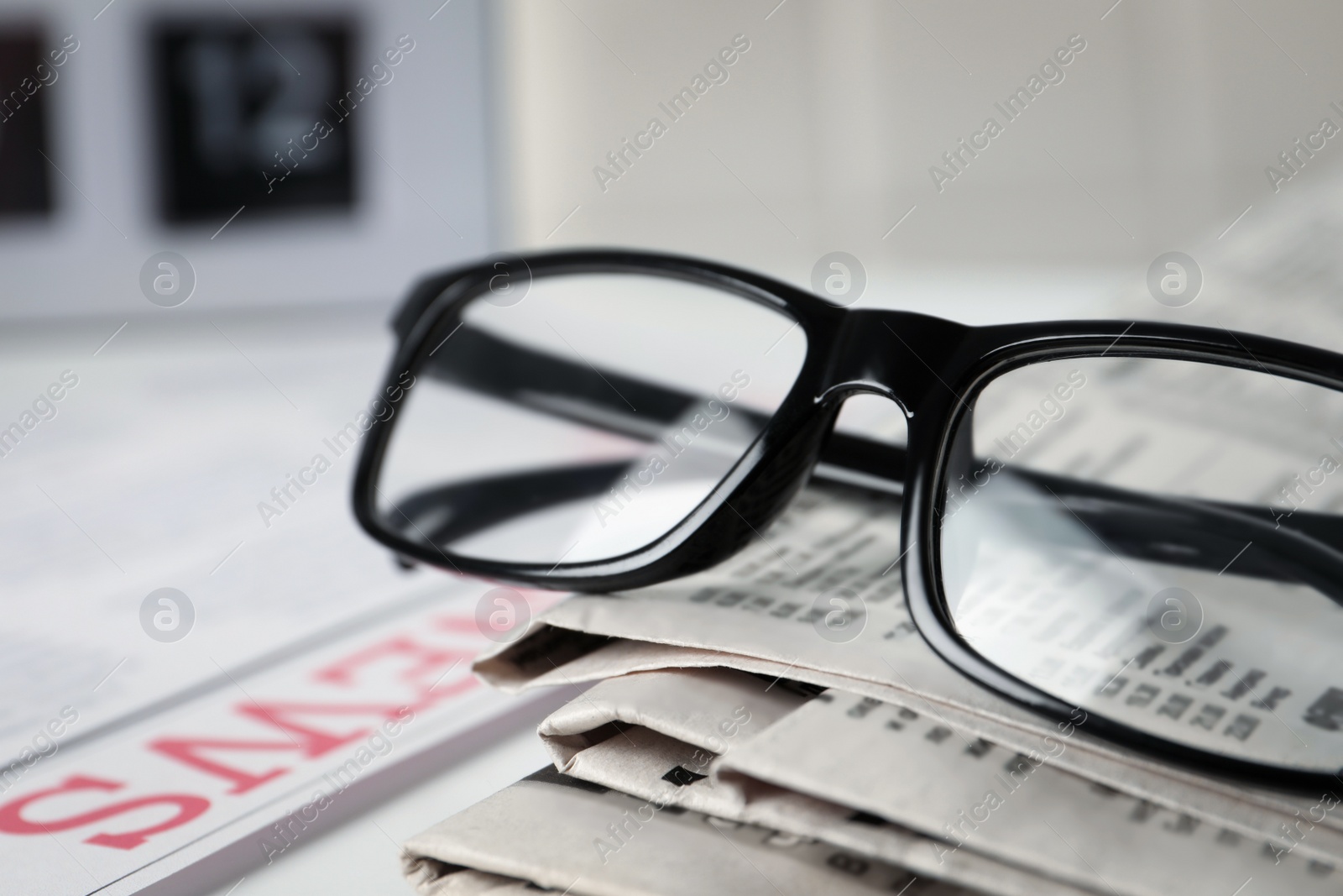 Photo of Glasses on stack of newspapers, closeup view