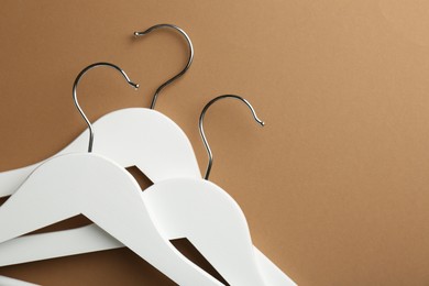 White hangers on brown background, top view. Space for text