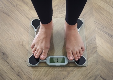 Photo of Woman using scale on floor, closeup. Overweight problem after New Year party